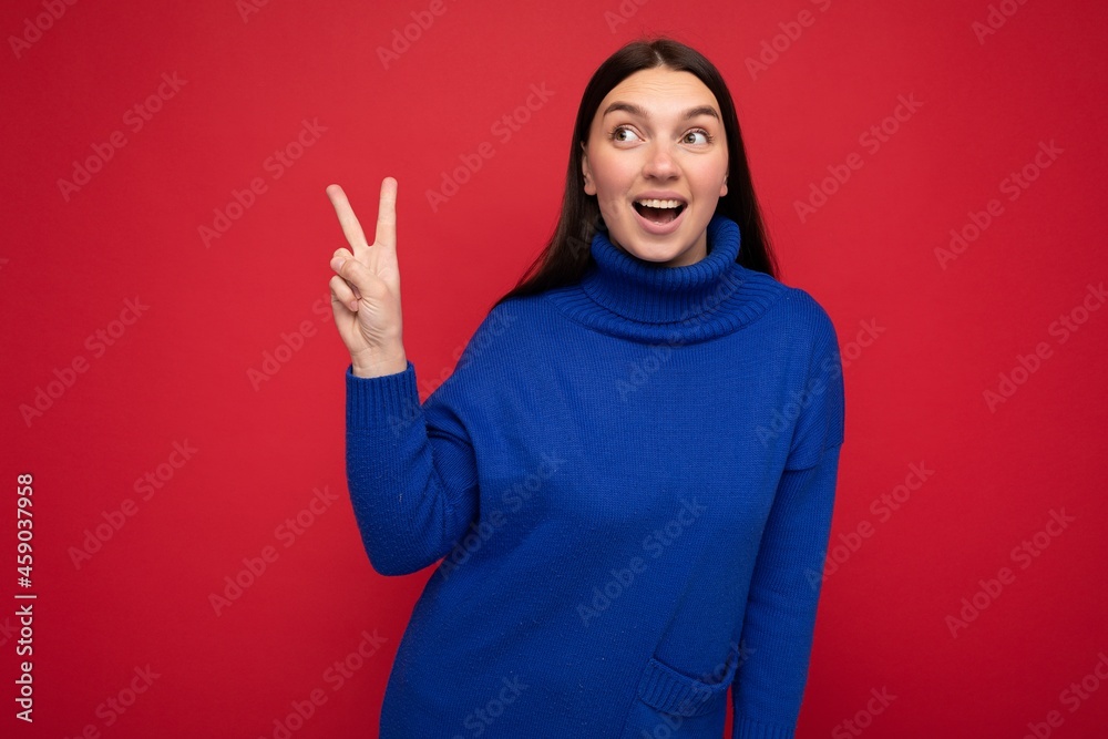 Photo of young positive happy smiling beautiful woman with sincere emotions wearing stylish clothes isolated over background with copy space and showing peace gesture with two fingers Photo of young positive happy smiling beautiful woman with sincere emotions wearing stylish clothes isolated over background with copy space and showing peace gesture with two fingers