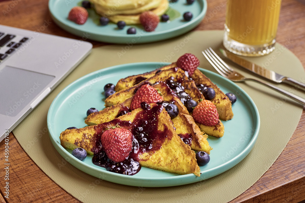 Delicious dish of toasts with jam strawberries and blue berries served with orange juice Delicious dish of toasts with jam strawberries and blue berries served with orange juice