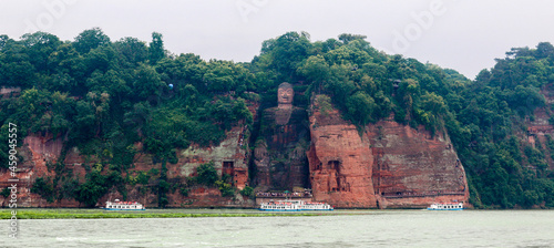 Panorama shot of the Ancient Giant Leshan Buddha in Leshan, Chengdu, Sichuan, China, the largest stone carving of the Buddha in the world, with three tour boats in front