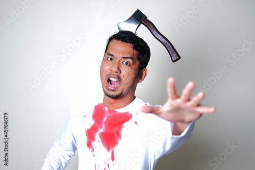 Bloody man screaming while got axe stuck in his head. Halloween concept photo