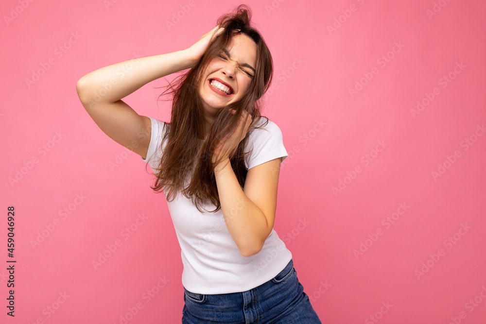 Portrait of positive cheerful fashionable woman in casual white t-shirt for mock up isolated on pink background with copy space