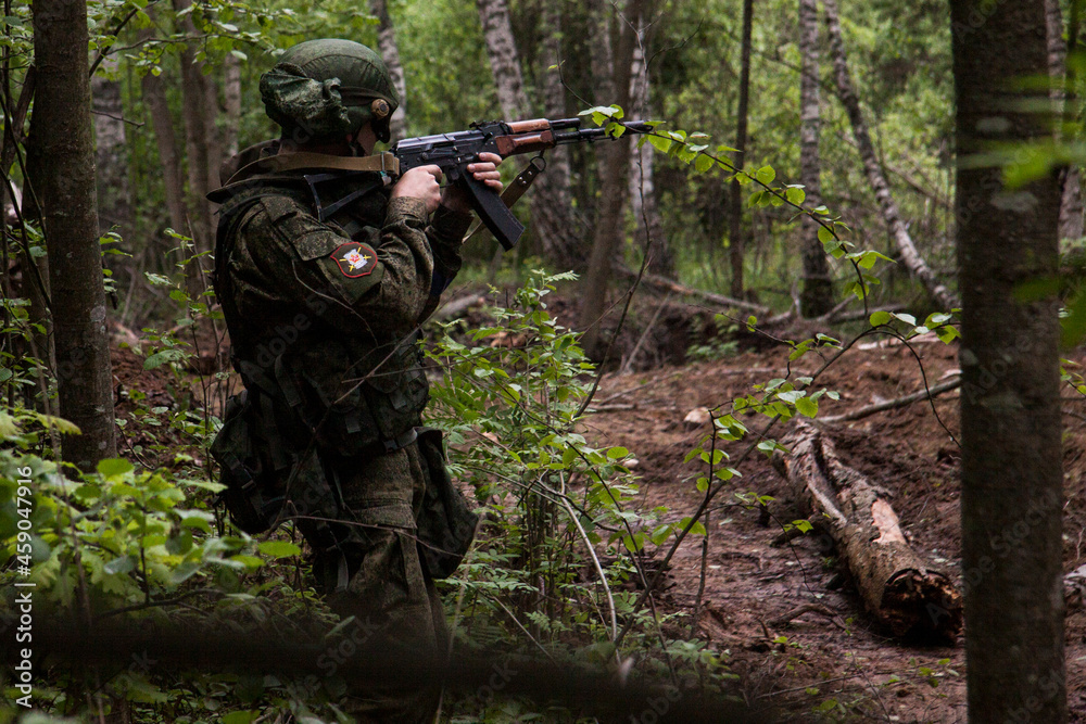 A soldier with a machine gun is aiming in the thicket. Russian Army