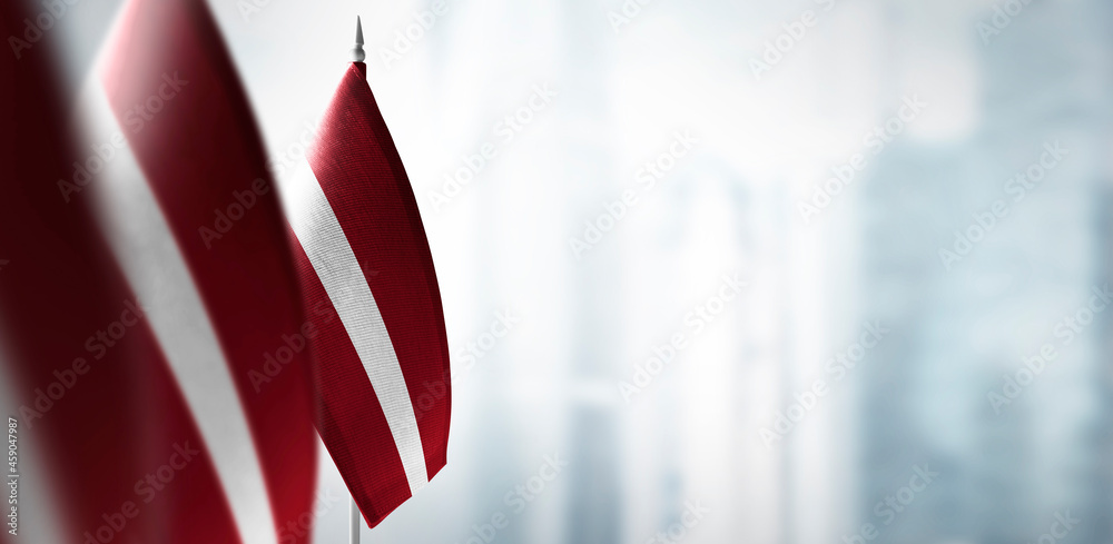Ταπετσαρία Small flags of Latvia on a blurry background of the city