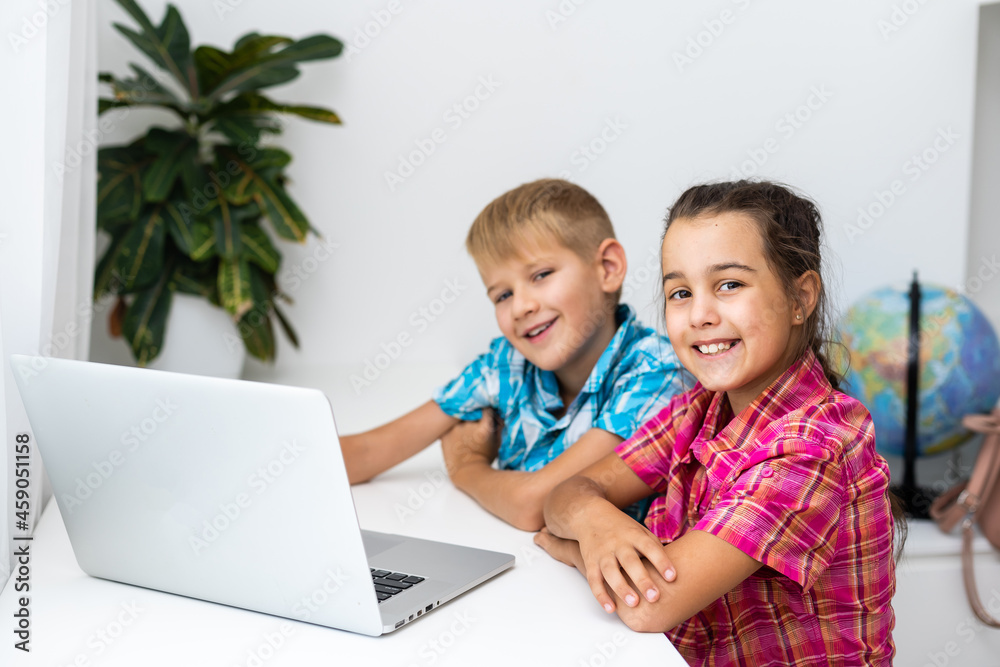Cute children use laptop for education, online study, home studying, Boy and Girl have homework at distance learning. Lifestyle concept for home schooling. Cute children use laptop for education, online study, home studying, Boy and Girl have homework at distance learning. Lifestyle concept for home schooling.