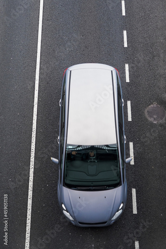 Top down view on a silver mini van on a dark asphalt road. Motion blur. Transportation concept. Vertical image