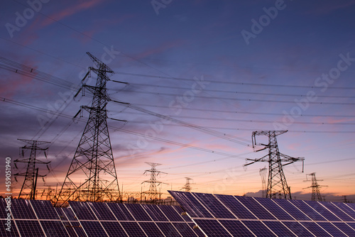 Transmission towers and solar panels are clean energy concepts. Sunset background