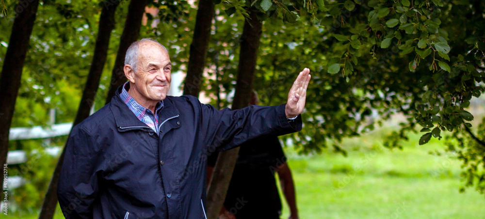 A happy older man waves a greeting A happy older man waves a greeting