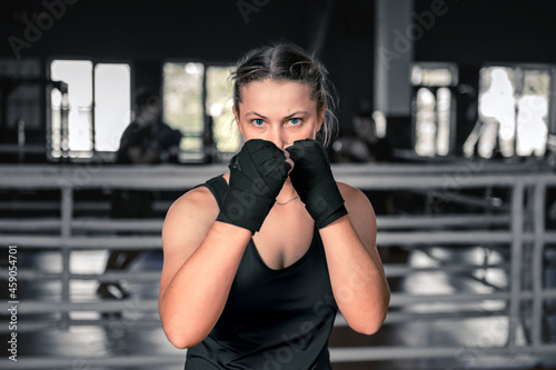 Young woman getting ready for exercise in the gym. Woman boxer getting ready near the ring