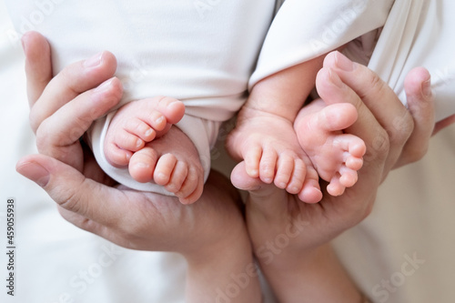 Tableau sur toile Mom and dad hands hold small legs of their two newborn twin babies