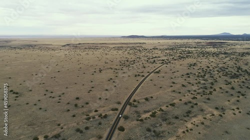 Wide aerial as car drives down highway in scrub covered desert near wupatki, 4K photo