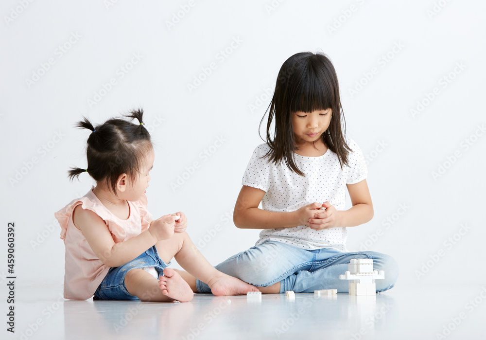 Cute Asian little female sisters playing toys indoors Cute Asian little female sisters playing toys indoors