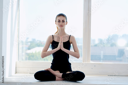 woman sitting in lotus position meditation rest near window