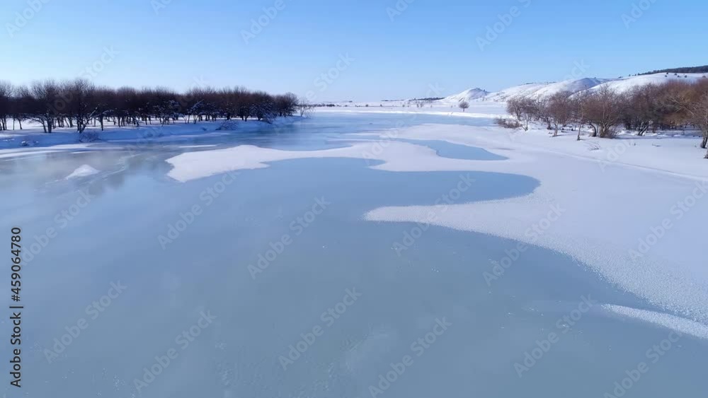 Panning forward shot of a small river covered with snow and ice, aerial view of the beautiful winter scene Panning forward shot of a small river covered with snow and ice, aerial view of the beautiful winter scene
