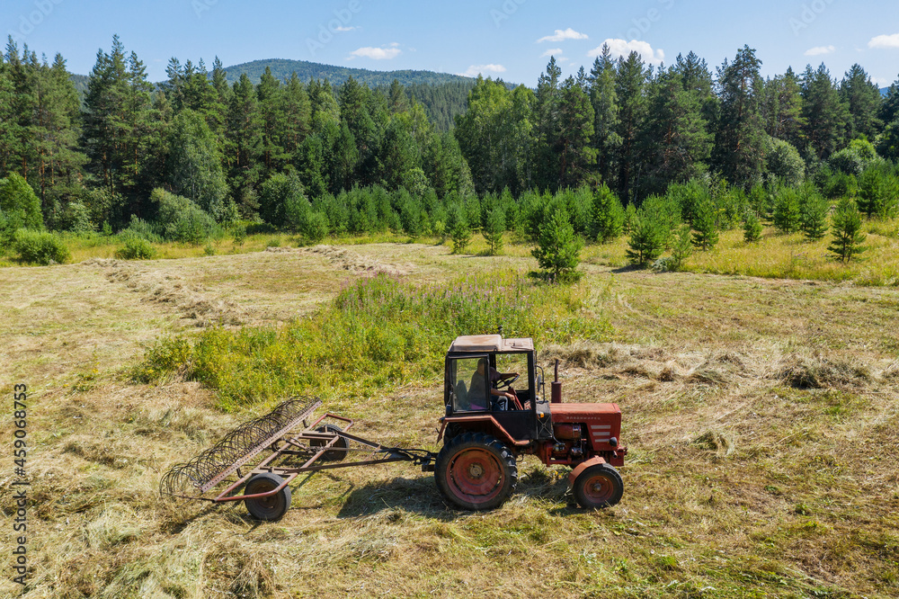 Obraz premium Southern Urals. Mountain meadow. Tractor on the hayfield. Aerial view.