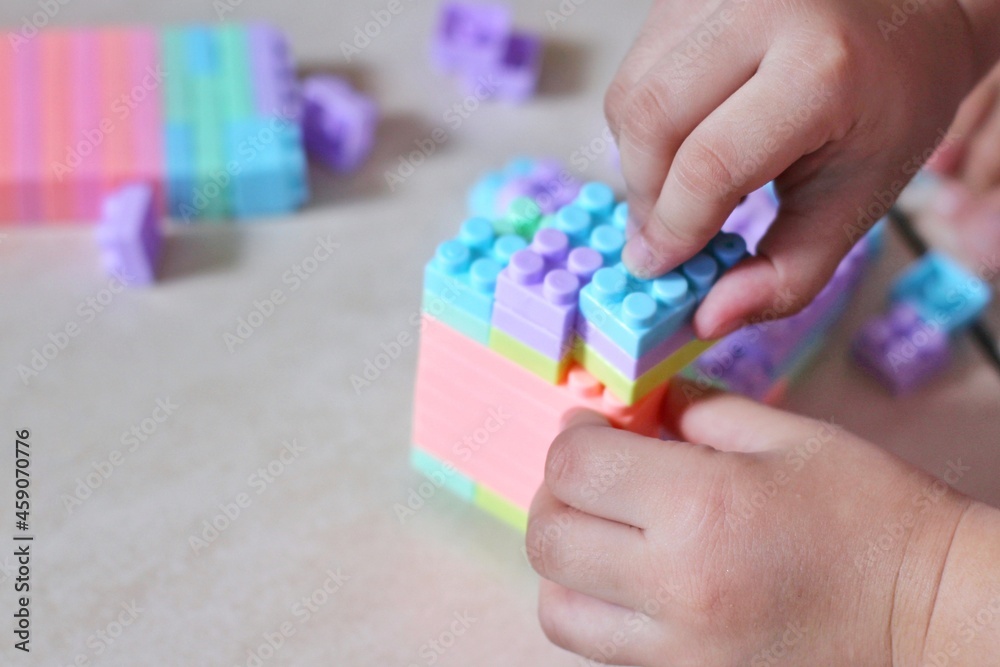 Selective focus image of child's hands playing with colorful plastic blocks. Copy space for text