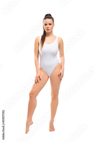 Young, fit and beautiful brunette woman in white swimsuit isolated on white background. Healthcare, diet, sport and fitness.