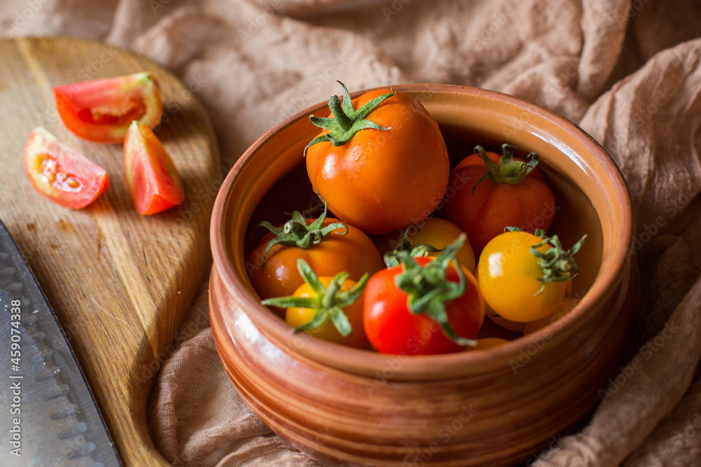 Fresh tomatoes in earthenware. Red, orange and yellow tomatoes on a brown background. Picking tomatoes Fresh tomatoes in earthenware. Red, orange and yellow tomatoes on a brown background. Picking tomatoes
