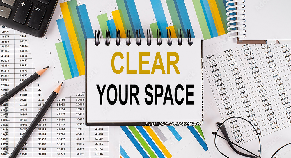 Closeup a notebook with text CLEAR YOUR SPACE , business concept image on chart background Closeup a notebook with text CLEAR YOUR SPACE , business concept image on chart background