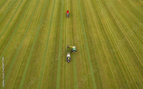 Harvester and tractor, agricultural machinery, collecting grass in the field.