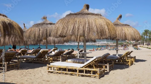 Tourists sunbathing and Beach Straw umbrellas on the beach of Palma de Mallorca - Spain