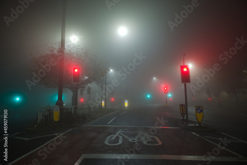 Colored traffic lights and white street lamps shine through thick fog