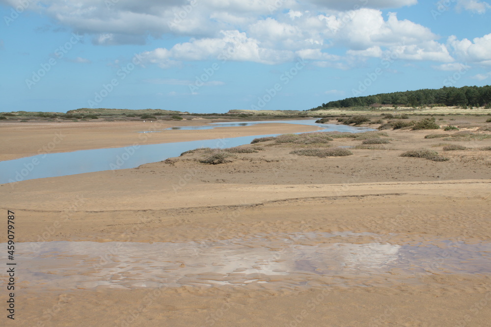 Beautiful landscape of the vast sandy beach at Holkham in Norfolk East Anglia with white puffy clouds in blue skies in Summer holiday day time