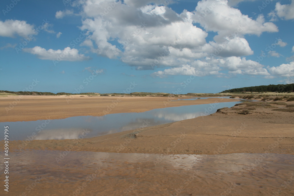 Landscape of beautiful sandy beach with no people and sands stretched to horizon with white puffy clouds reflected in the water pools in Holkham north Norfolk East Anglia uk Landscape of beautiful sandy beach with no people and sands stretched to horizon with white puffy clouds reflected in the water pools in Holkham north Norfolk East Anglia uk