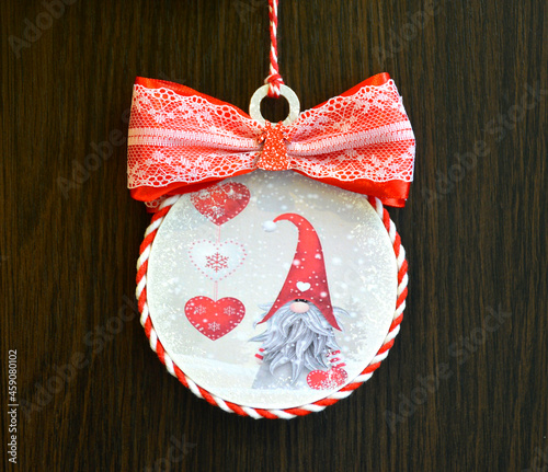 Christmas toy with a red bow, a gnome in a red cap and hearts with snowflakes on the background of a wooden board. christmas and new year celebration concept photo