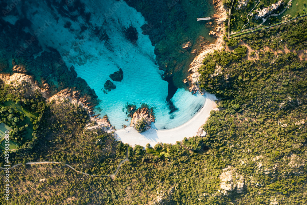 View from above, stunning aerial view of a green coast with the beautiful Prince Beach (Spiaggia del Principe) a white sand beach bathed by a turquoise water. Sardinia, Italy.