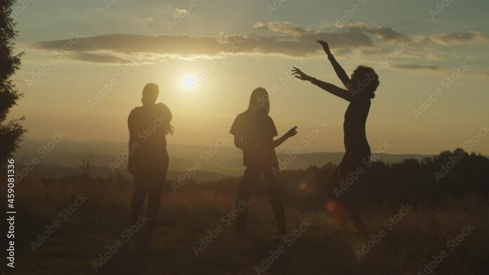 Silhouette of elegant attractive multiracial women having fun , dancing gracefully, enjoying recreation and freedom, expressing carefree mood, positivity and happiness on mountain top at sunset.