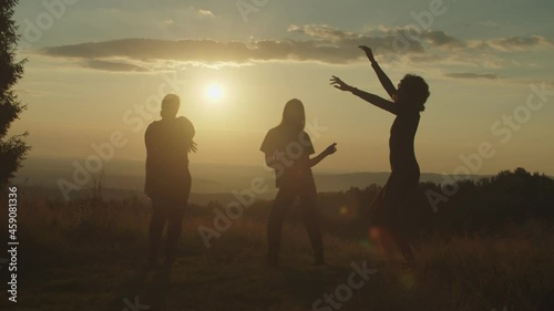 Silhouette of elegant attractive multiracial women having fun , dancing gracefully, enjoying recreation and freedom, expressing carefree mood, positivity and happiness on mountain top at sunset.