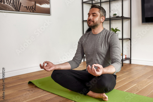 Middle-aged Caucasian man meditate practice yoga at home