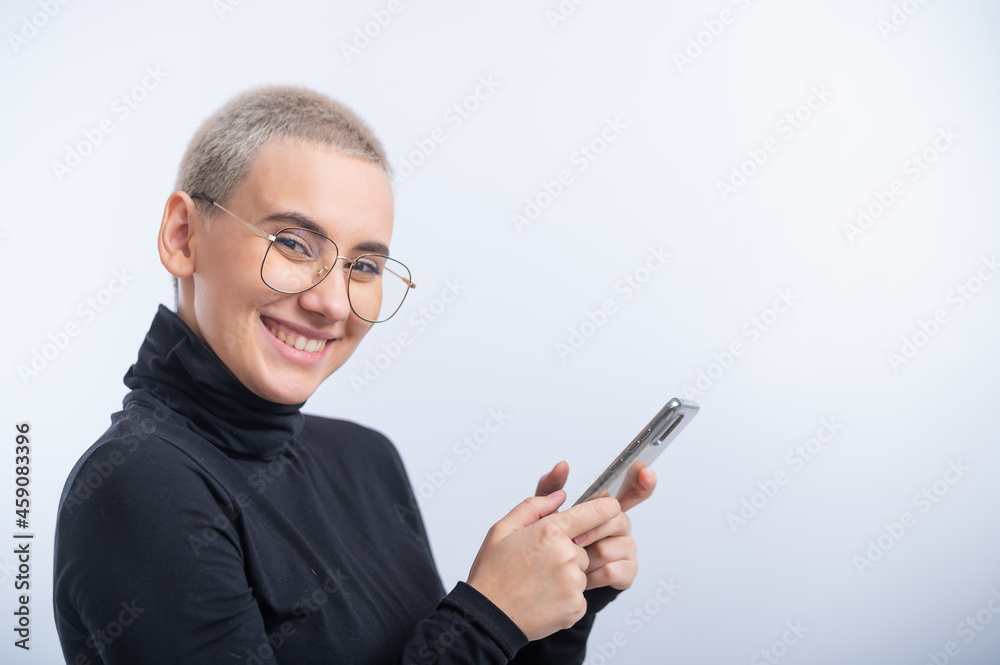 Young caucasian woman with short hair uses a smartphone on a white background. Young caucasian woman with short hair uses a smartphone on a white background.
