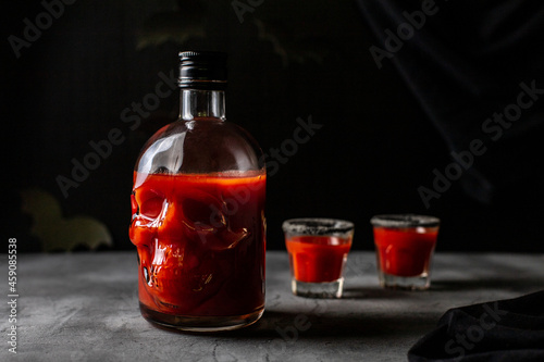 Tomato cocktail in a skull-shaped bottle and glasses. Drink for Halloween party