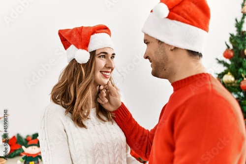 Young hispanic couple smiling happy wearing christmas hat at home.