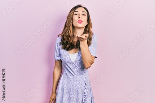 Young hispanic girl wearing casual clothes looking at the camera blowing a kiss with hand on air being lovely and sexy. love expression.