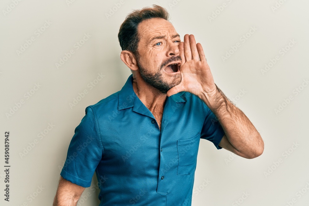 Middle age man wearing casual clothes shouting and screaming loud to side with hand on mouth. communication concept. Middle age man wearing casual clothes shouting and screaming loud to side with hand on mouth. communication concept.