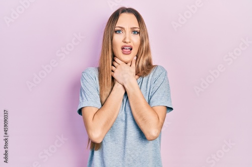 Young blonde girl wearing casual t shirt shouting and suffocate because painful strangle. health problem. asphyxiate and suicide concept.
