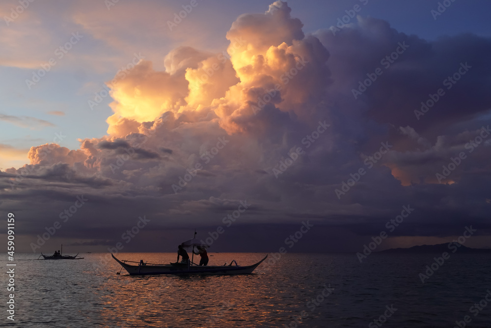 Traditional evening banka boat fishing. Approaching storm . Sunset at Aninuan beach Philippines