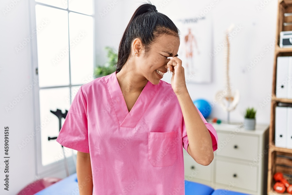 Young hispanic woman working at pain recovery clinic smelling something stinky and disgusting, intolerable smell, holding breath with fingers on nose. bad smell Young hispanic woman working at pain recovery clinic smelling something stinky and disgusting, intolerable smell, holding breath with fingers on nose. bad smell