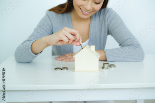 Asia woman saving money with shaped house box
