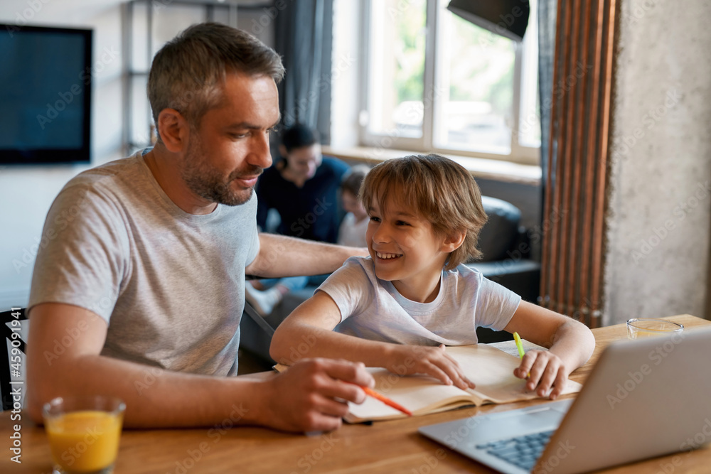 Smiling teen boy child study online on computer with dad Smiling teen boy child study online on computer with dad