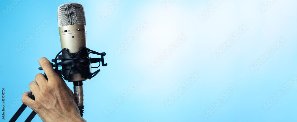 Man's hand holding a condenser microphone on a stand. Man's hand holding a condenser microphone on a stand.