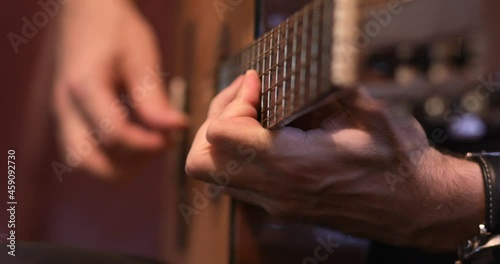 Musician plays classical acoustic guitar with nylon strings, close-up focus on musician's left hand on fingerboard
