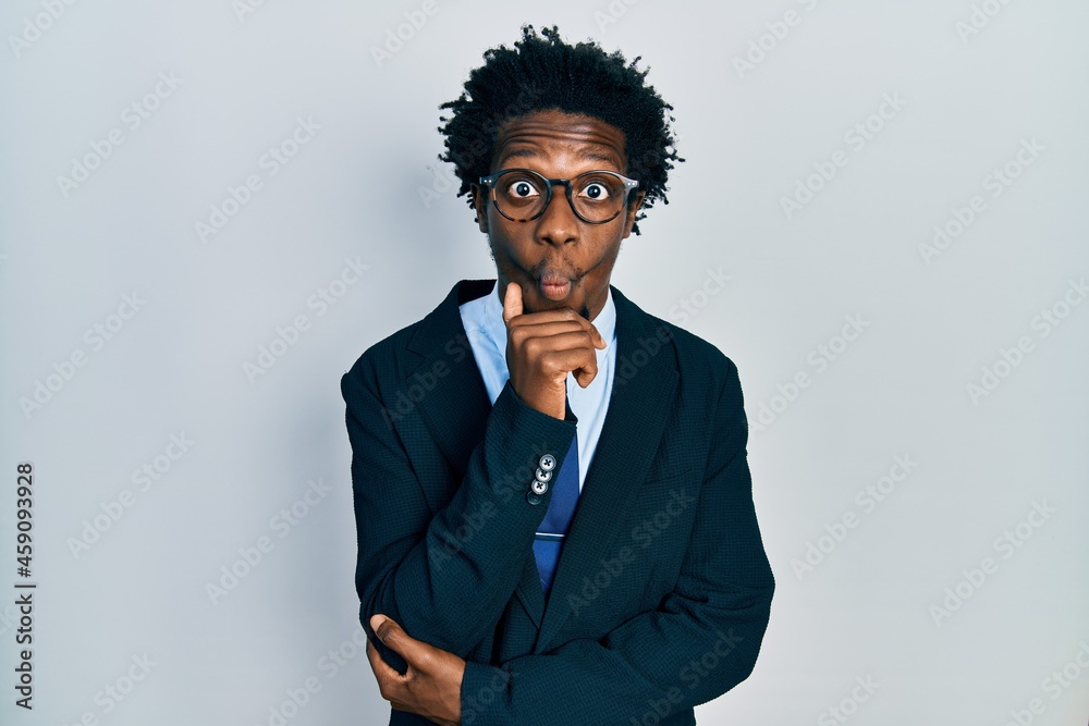 Young african american man wearing business suit and tie making fish face with mouth and squinting eyes, crazy and comical. Young african american man wearing business suit and tie making fish face with mouth and squinting eyes, crazy and comical.