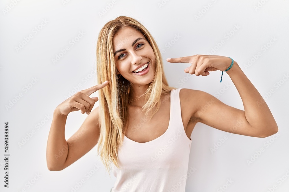 Blonde beautiful young woman standing over white isolated background smiling cheerful showing and pointing with fingers teeth and mouth. dental health concept. Blonde beautiful young woman standing over white isolated background smiling cheerful showing and pointing with fingers teeth and mouth. dental health concept.