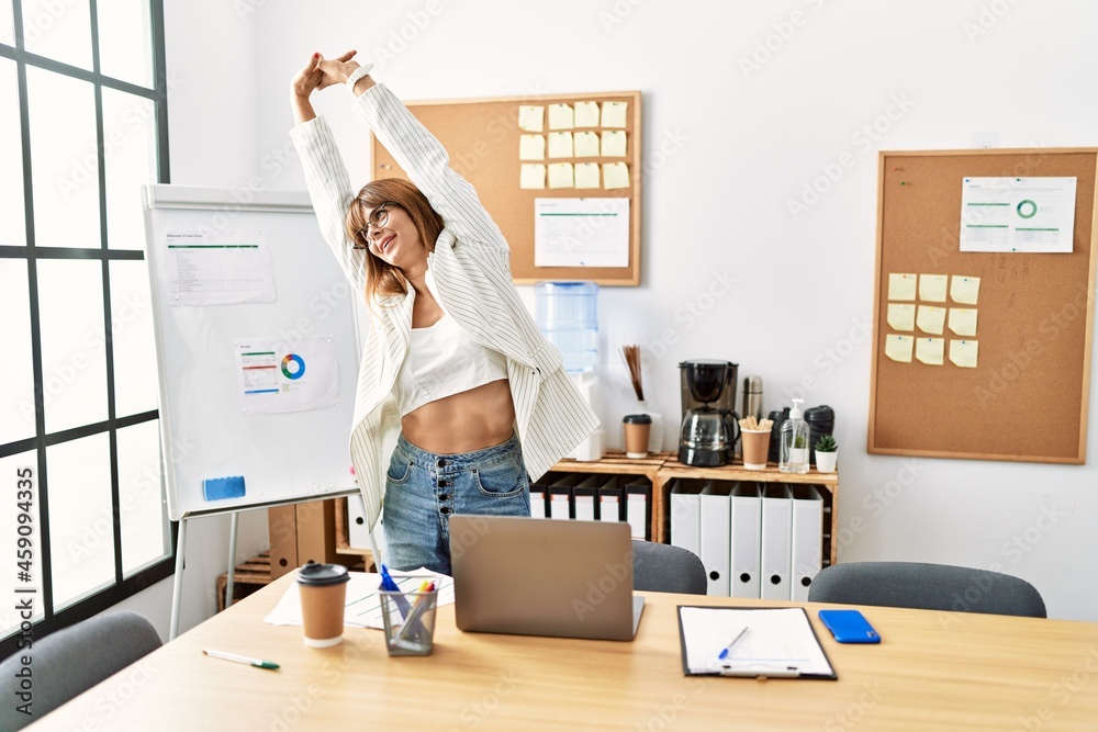 Young hispanic businesswoman tired stretching arms at the office. Young hispanic businesswoman tired stretching arms at the office.