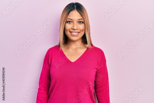 Beautiful hispanic woman wearing casual pink sweater with a happy and cool smile on face. lucky person.