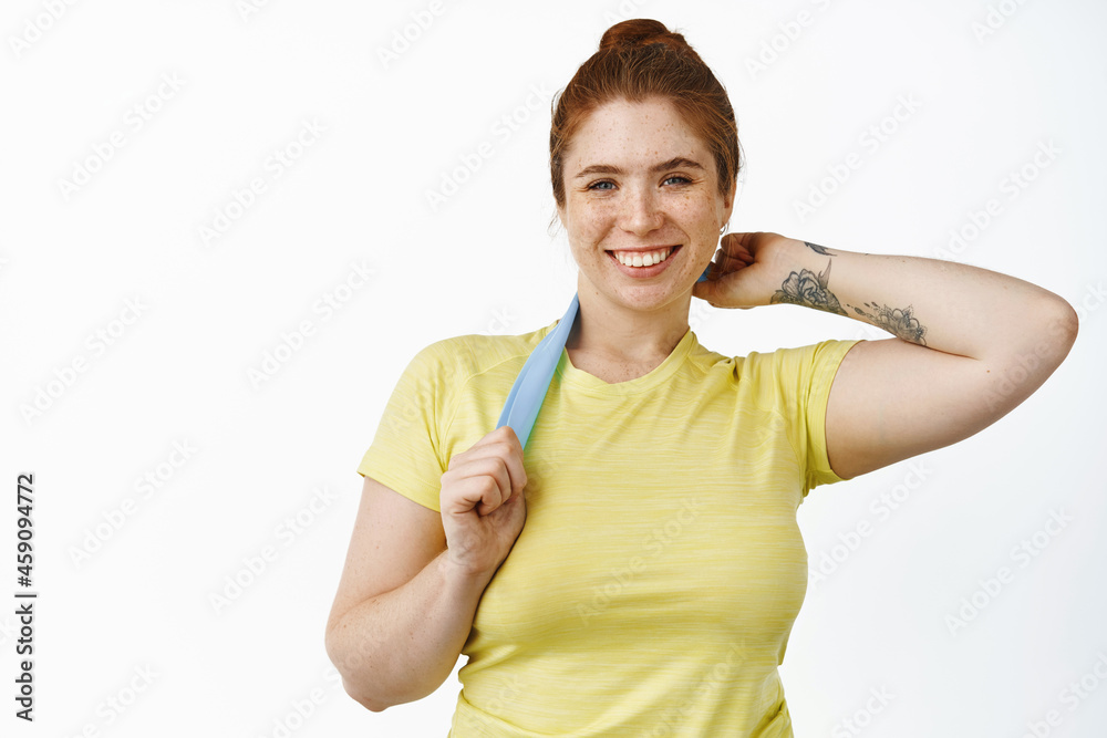 Young smiling chubby girl workout with elastic rope, doing fitness exercises with resitance band, standing over white background