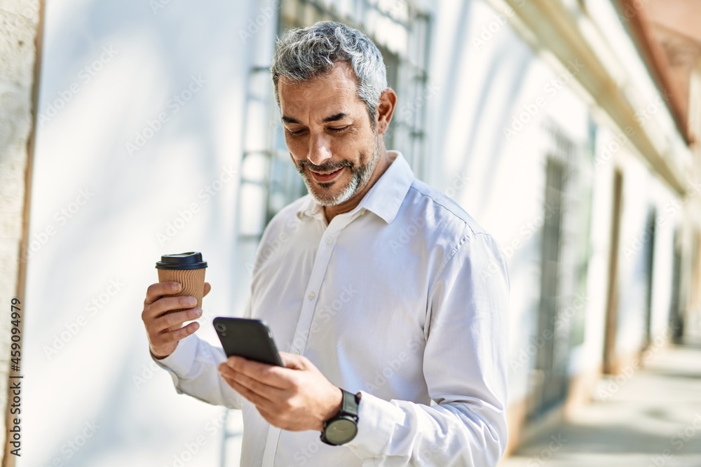 Middle age grey-haired man using smartphone drinking coffee at the city. Middle age grey-haired man using smartphone drinking coffee at the city.